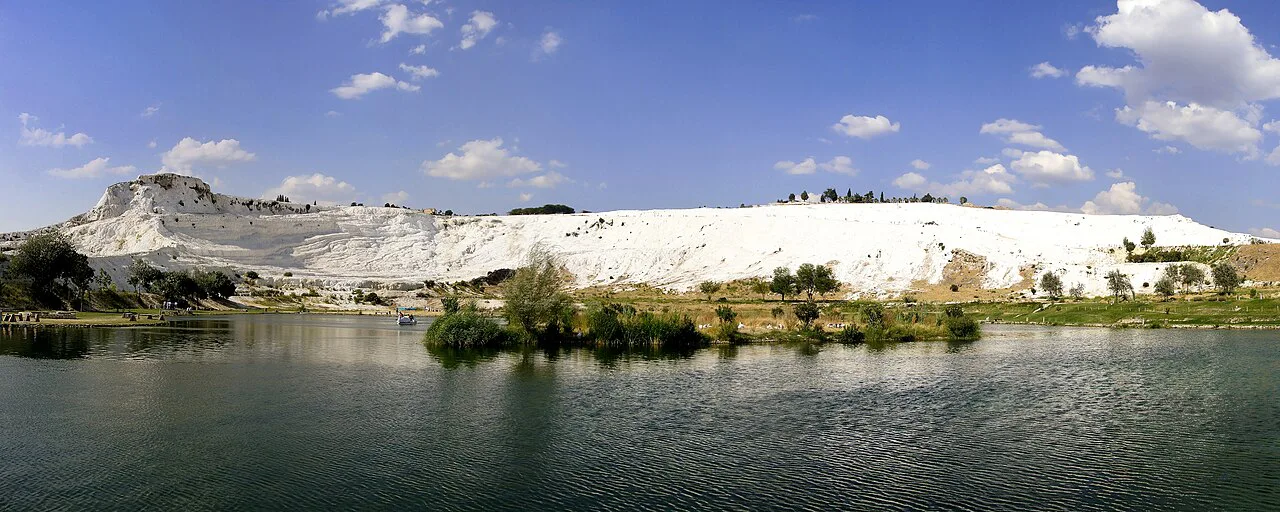 Pamukkale's travertine terraces above a lake.