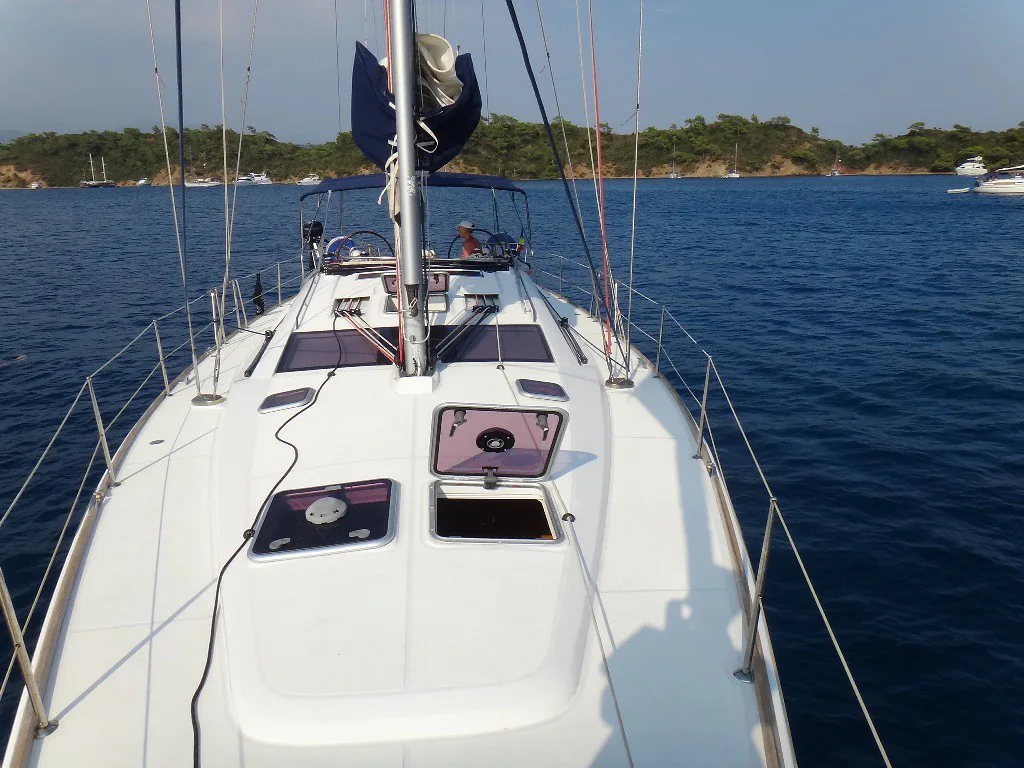 On deck of a sailing yacht at anchor in a wooded bay off the Turkish coast.