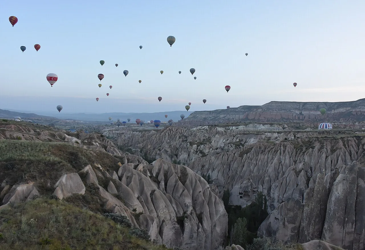 Balloons rising above the rock formations near Göreme at dawn.