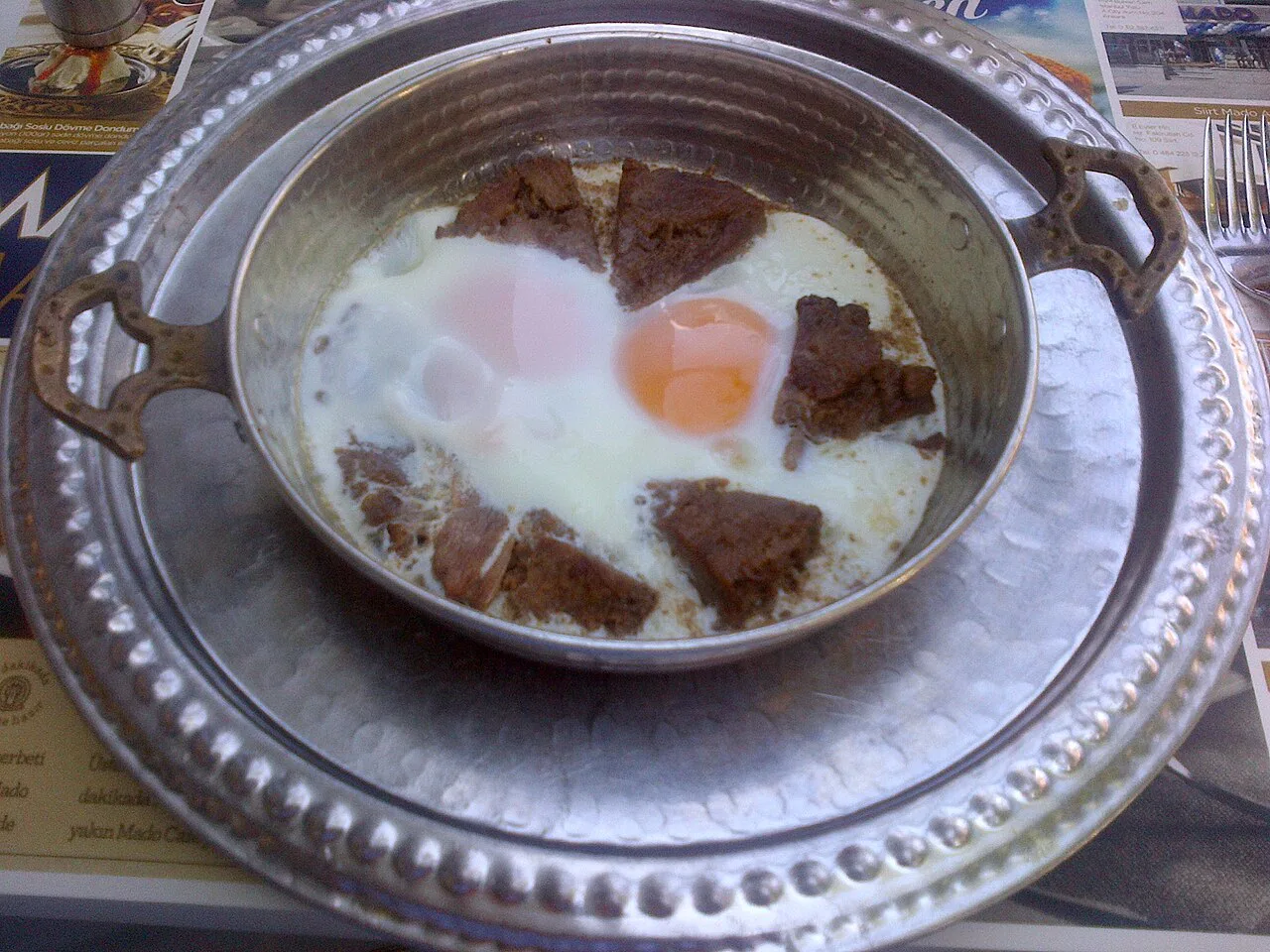 Sahanda kavurma, eggs fried with diced meat in a small two-handled pan.