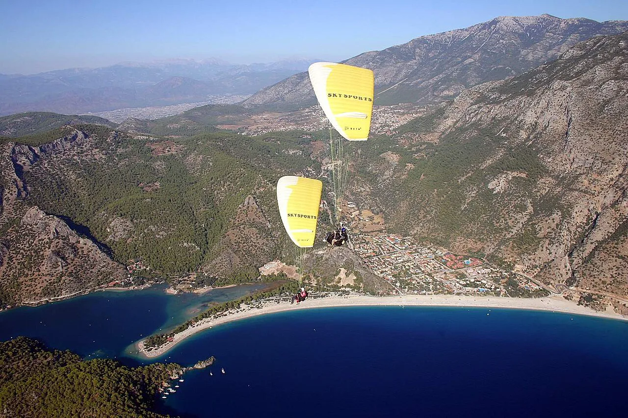 Tandem paragliders descending from Babadağ towards the beach at Ölüdeniz.