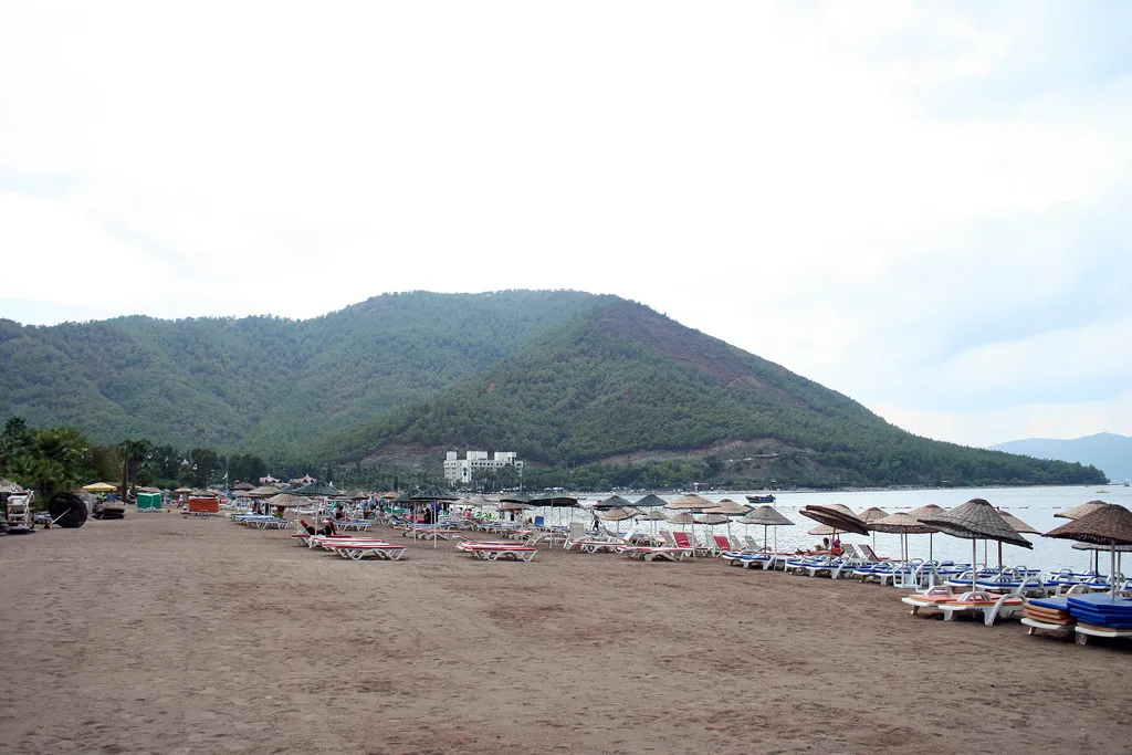 The beach at İçmeler with wooded hills behind.