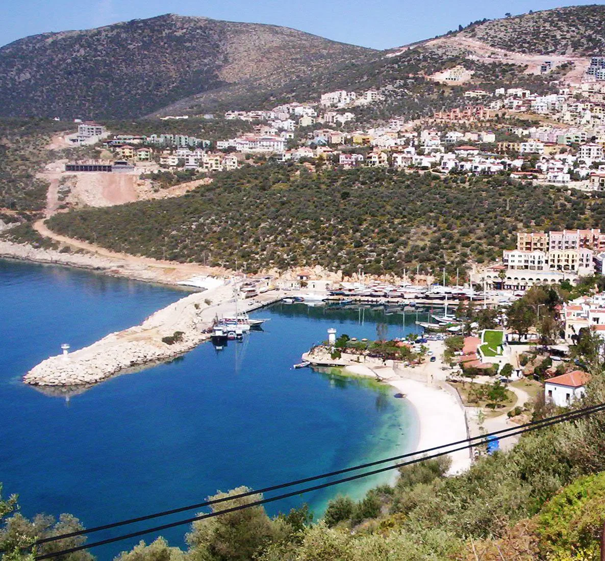 Kalkan's beach and harbour wall seen from above.