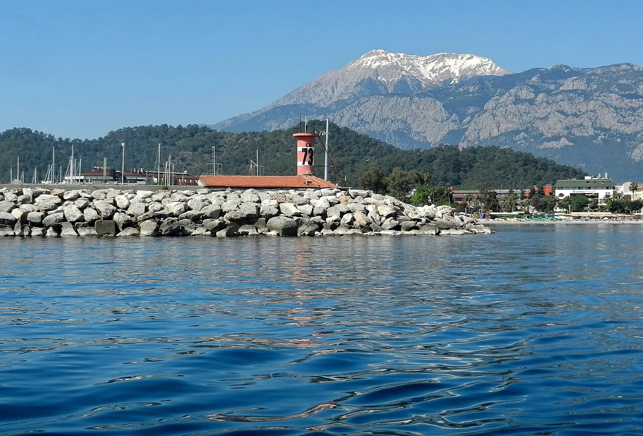 The breakwater of Kemer Marina with snow-capped mountains behind.