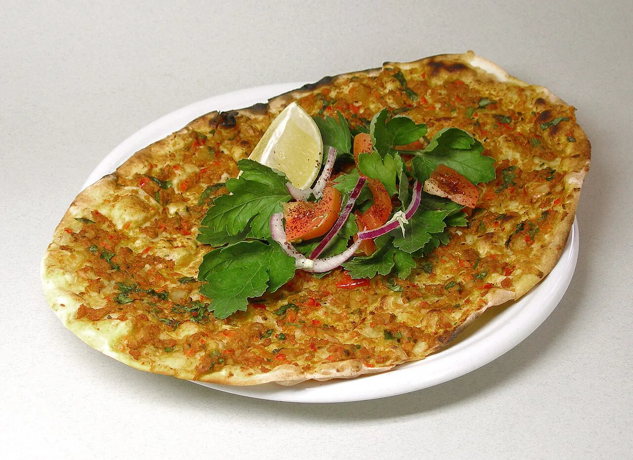 Lahmacun served with salad and a wedge of lemon.