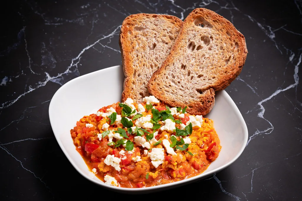 A bowl of menemen with slices of toasted bread.