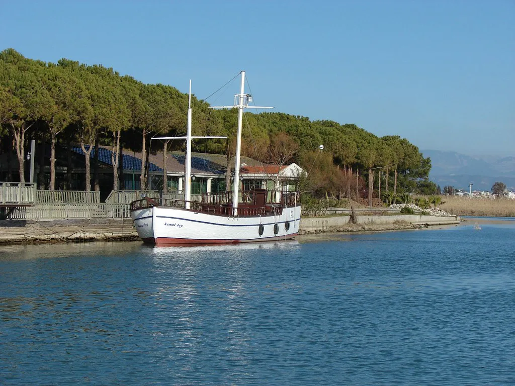 A wooden excursion boat moored beside pine woods at Belek.