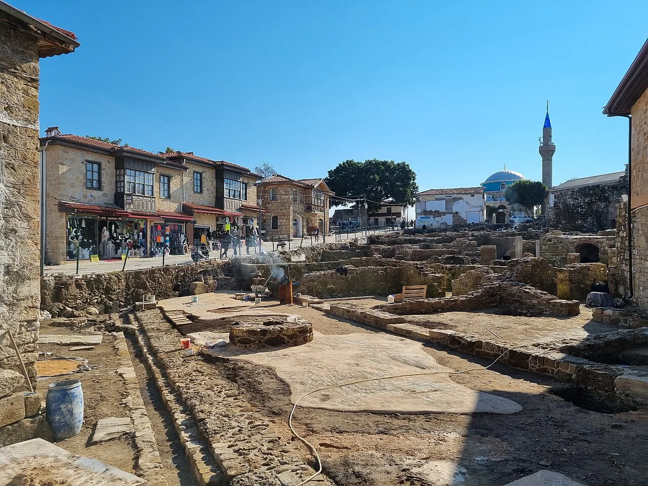 Excavated ruins beside houses and a minaret in Side.