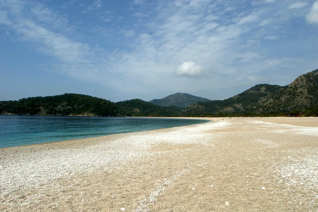 Ölüdeniz beach with forested hills behind.