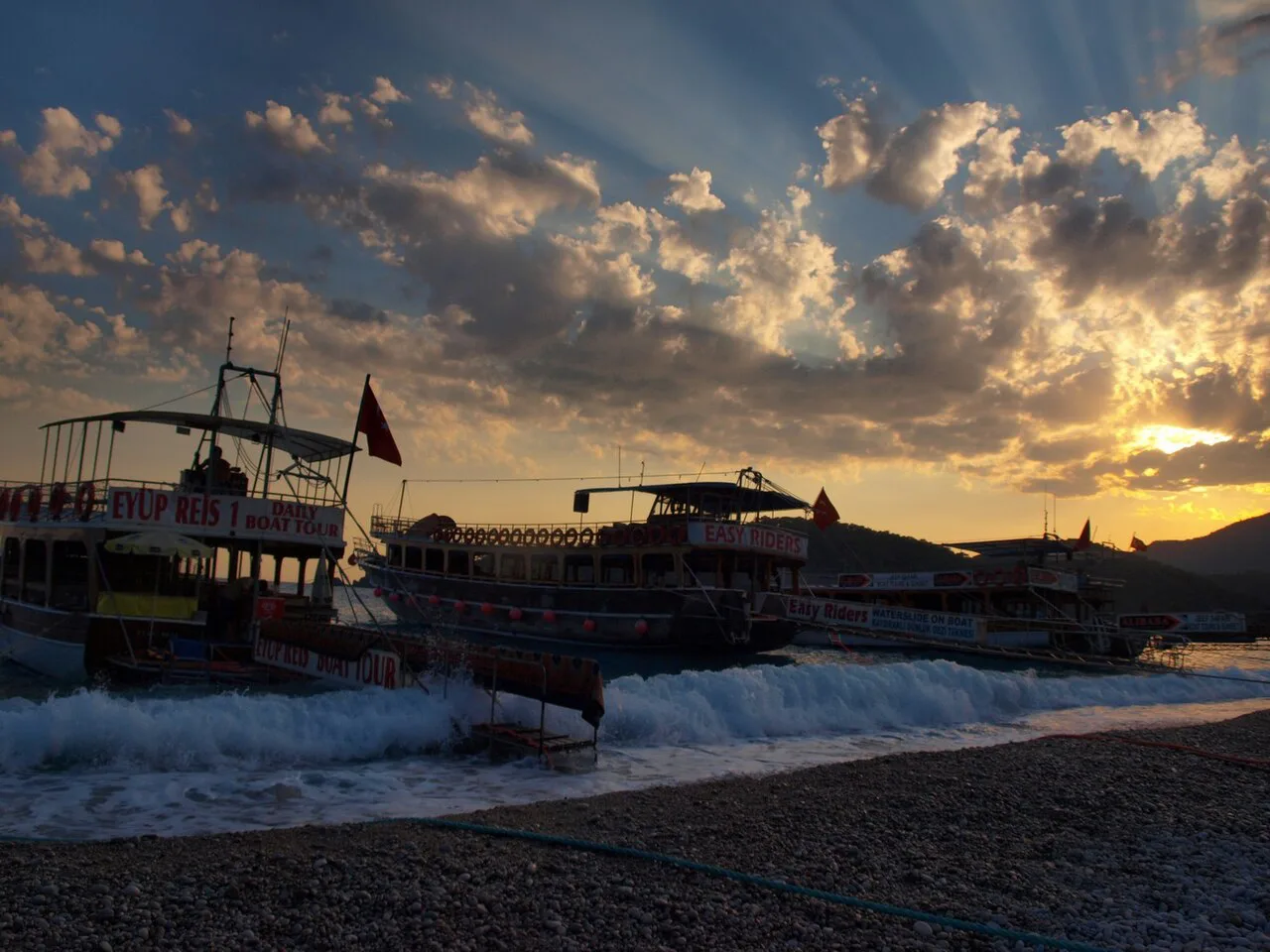 Boats pulled up on the beach at Ölüdeniz at sunset.