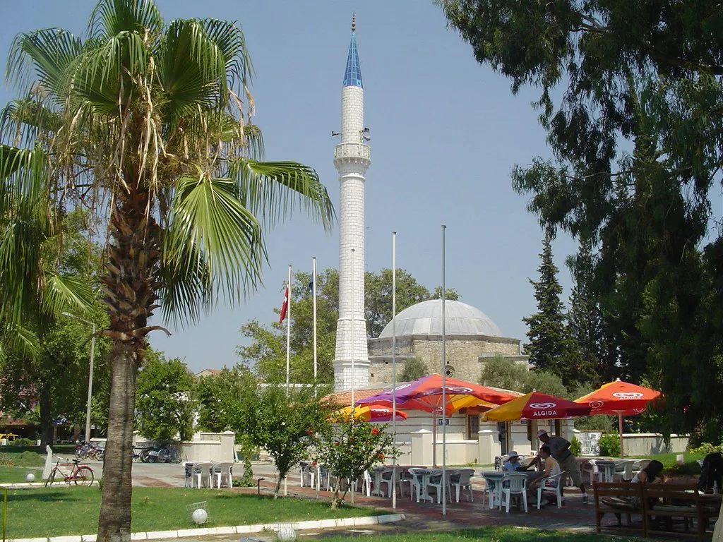 The mosque in Dalyan with café umbrellas beside it.