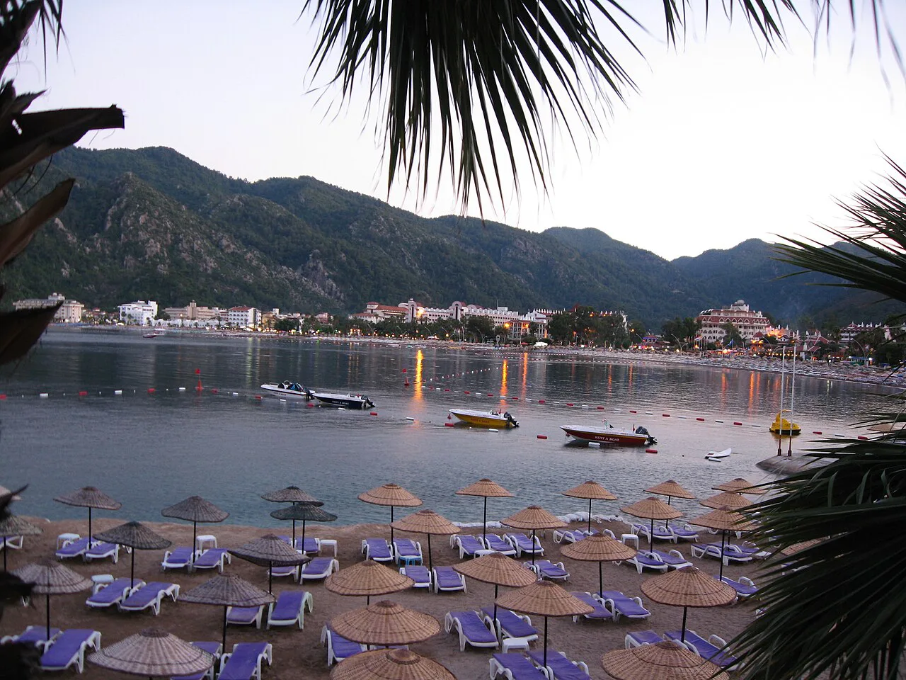 Sunloungers and parasols on İçmeler beach looking across the bay.