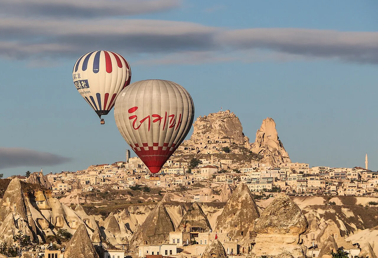 Hot-air balloons drifting past Uçhisar Castle in Cappadocia.