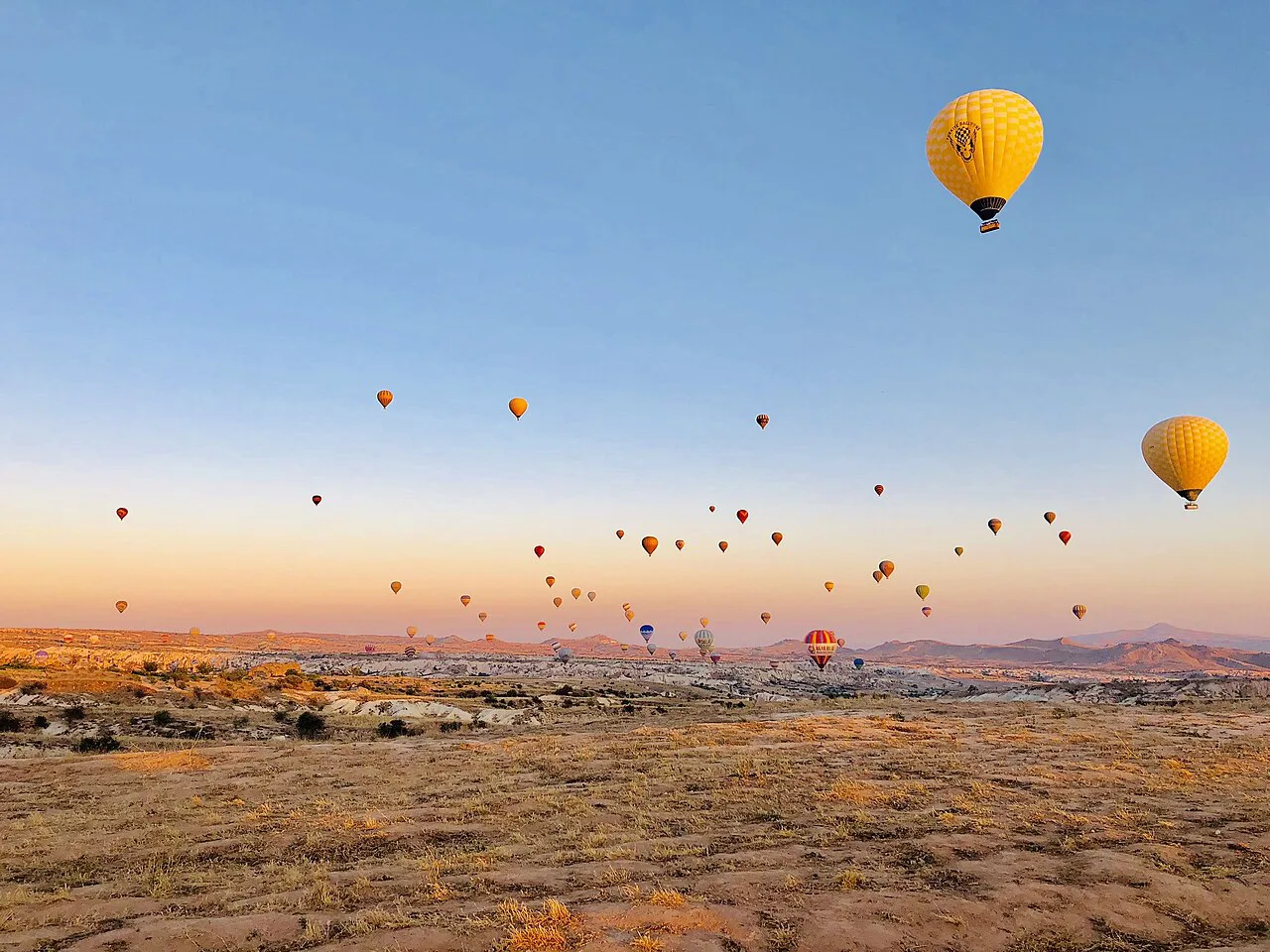 Hot-air balloons over Cappadocia at sunrise.
